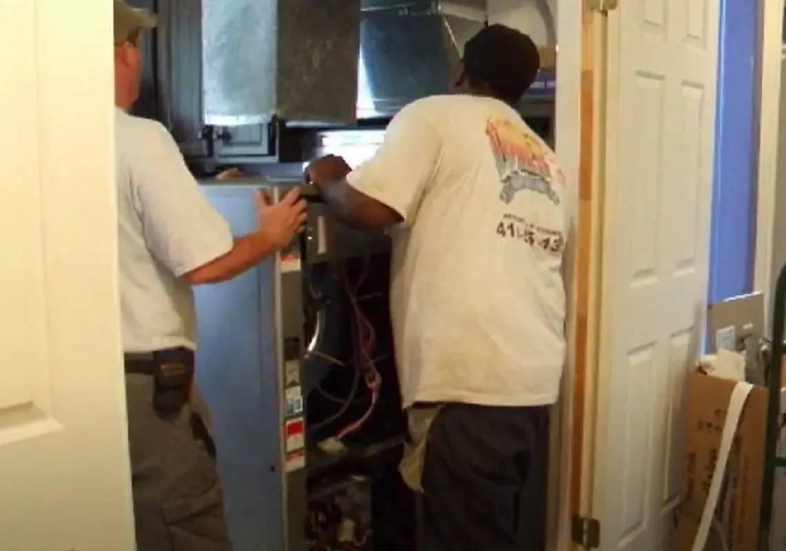 Two technicians installing an HVAC unit in a residential setting.